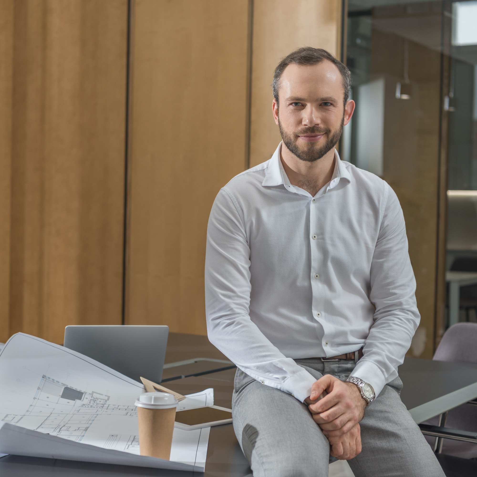 handsome architect sitting on table with plans at office